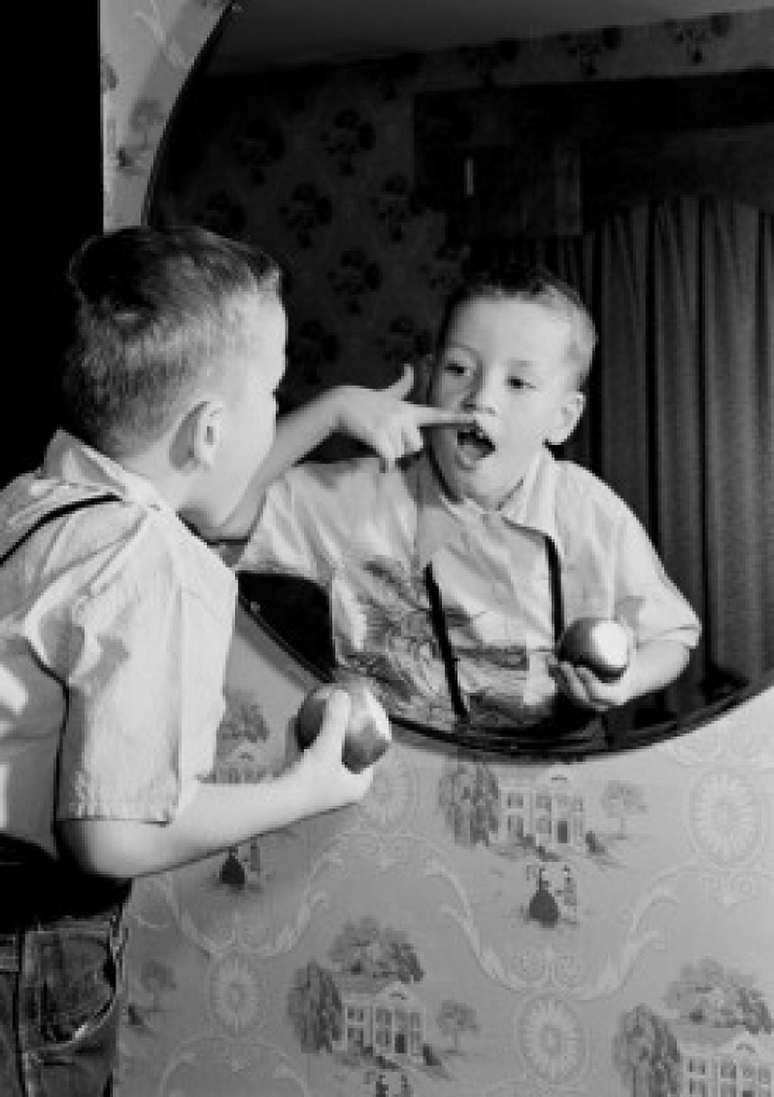 Over shoulder view of boy holding apple examining gap between teeth in mirror Canvas Art - (18 x 24)