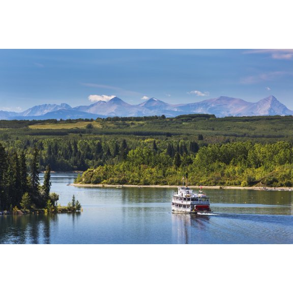 Paddlewheel boat on lake with tree lined shoreline hills and mountains in the background and blue sky and clouds Calgary Alberta Canada Canvas Art - Michael Interisano Design Pics (38 x 24)
