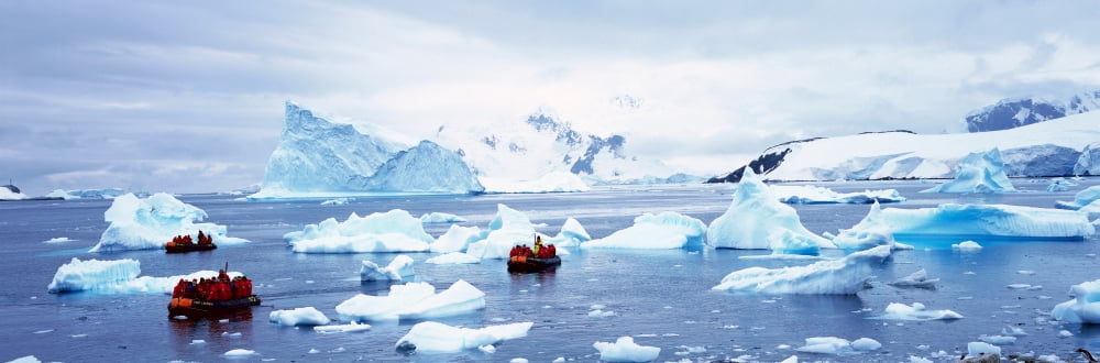 Panoramic view of ecological tourists in inflatable Zodiac boat with glaciers and icebergs in Paradise Harbor Antarctica Canvas Art - Panoramic Images (36 x 12)