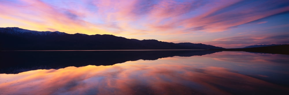 Panoramic view at sunset of flooded salt flats and Panamint Range Mountains in Death Valley National Park California Canvas Art - Panoramic Images (27 x 9)