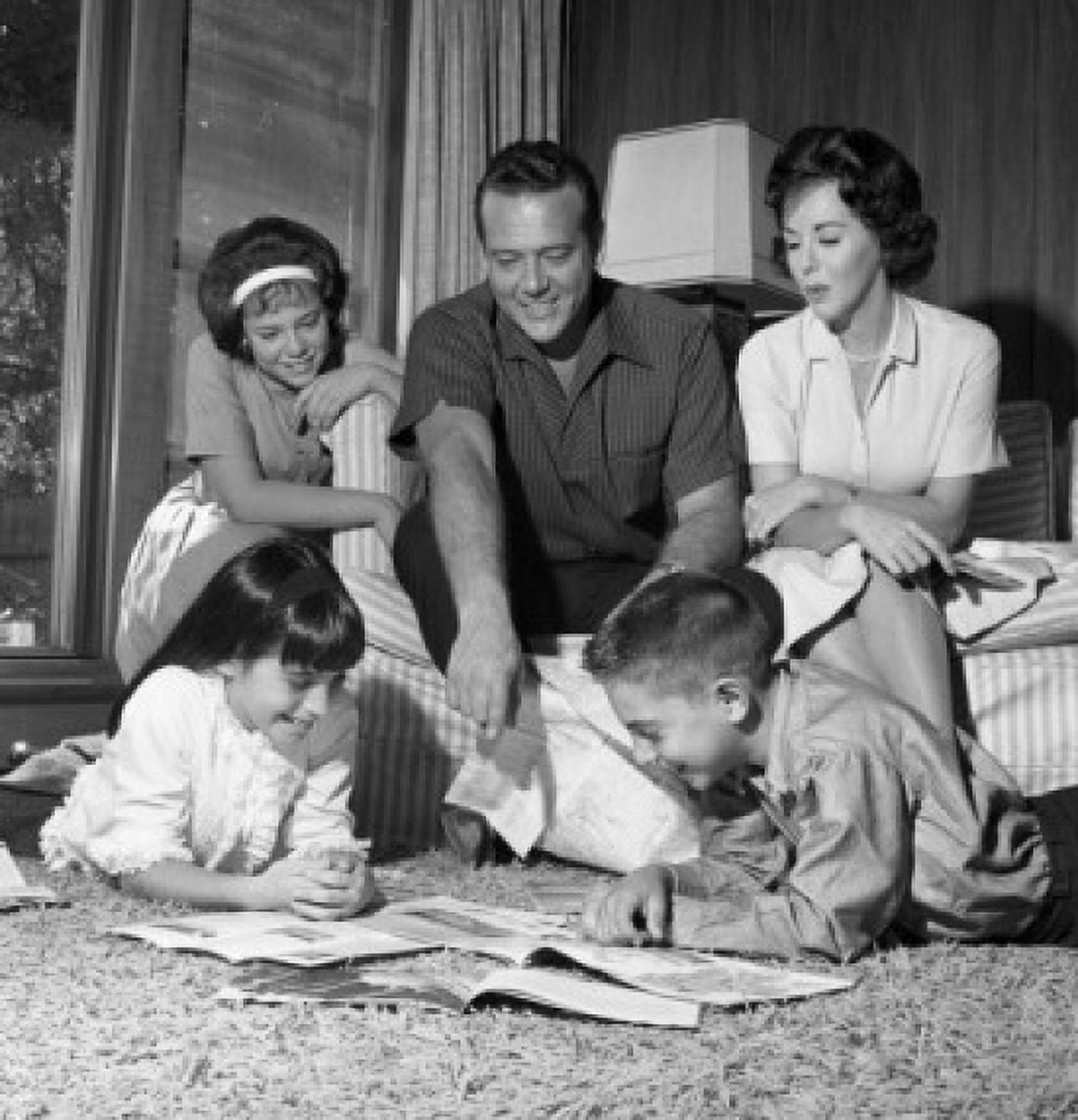 Parents sitting and looking at children reading on carpet Canvas Art - (18 x 24)
