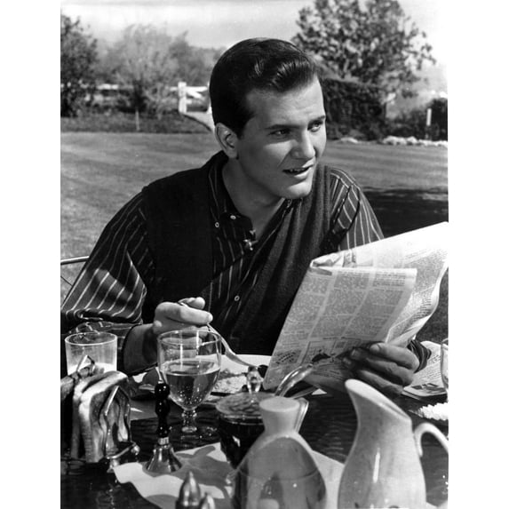 Pat Boone reading a newspaper and eating outdoors Photo Print (24 x 30)