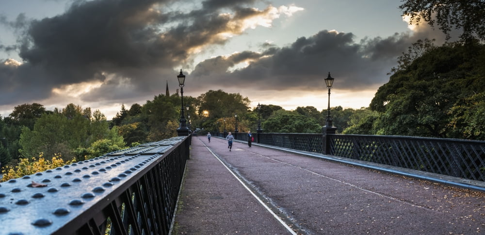 Pedestrians and a runner on a bridge with clouds glowing at sunset Newcastle Tyne and Wear England Canvas Art - John Short Design Pics (44 x 20)