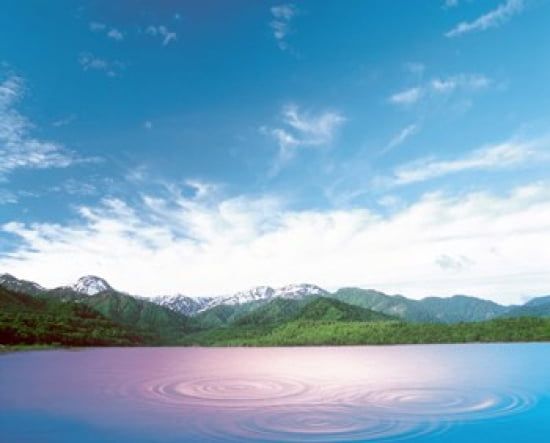 Pink light cast down on two rings in lavender water with deep blue sky and clouds over green mountains in distance Canvas Art - Panoramic Images (24 x 20)