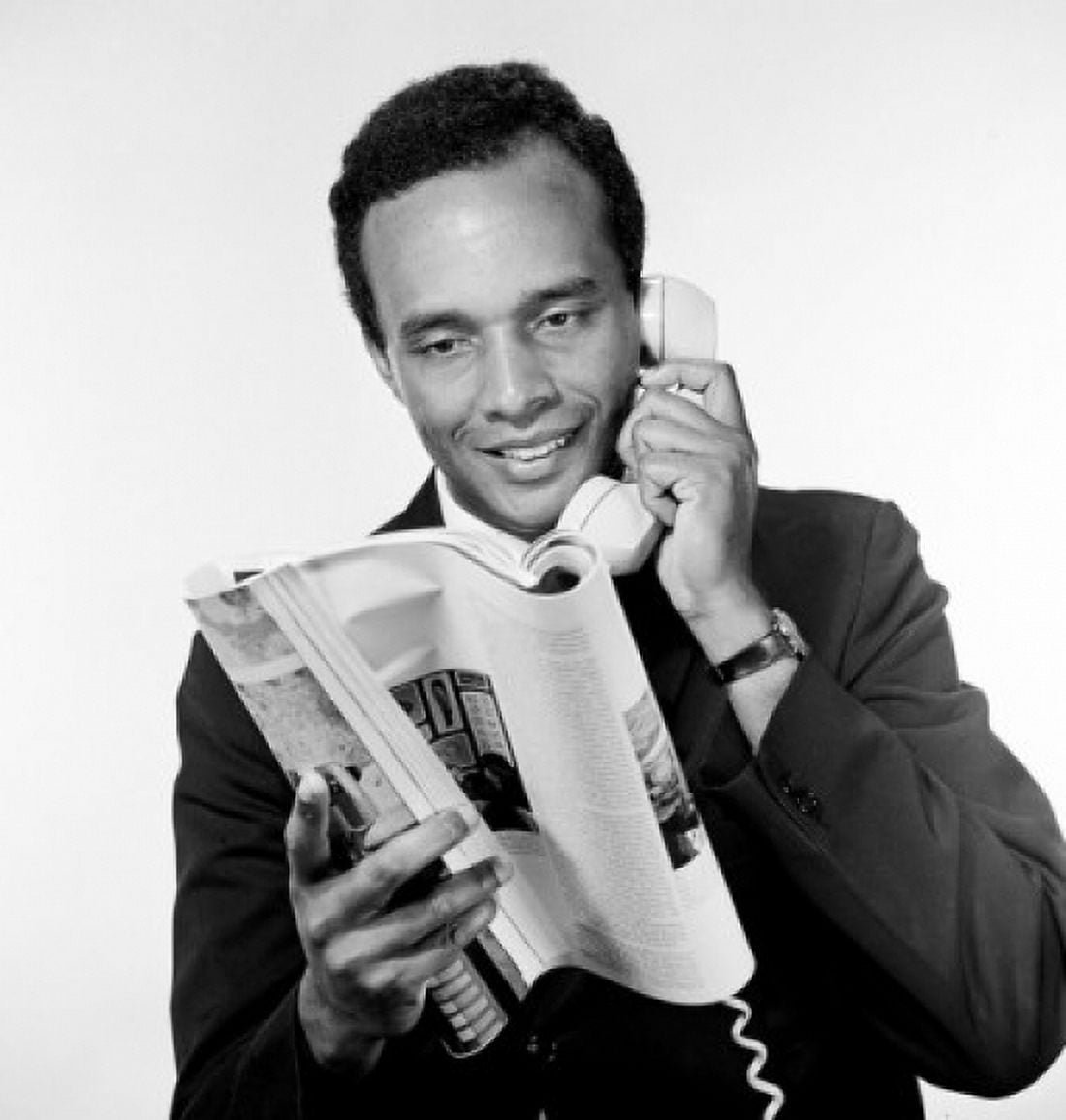 Portrait of African american man holding receiver and reading magazine studio shot Canvas Art - (18 x 24)