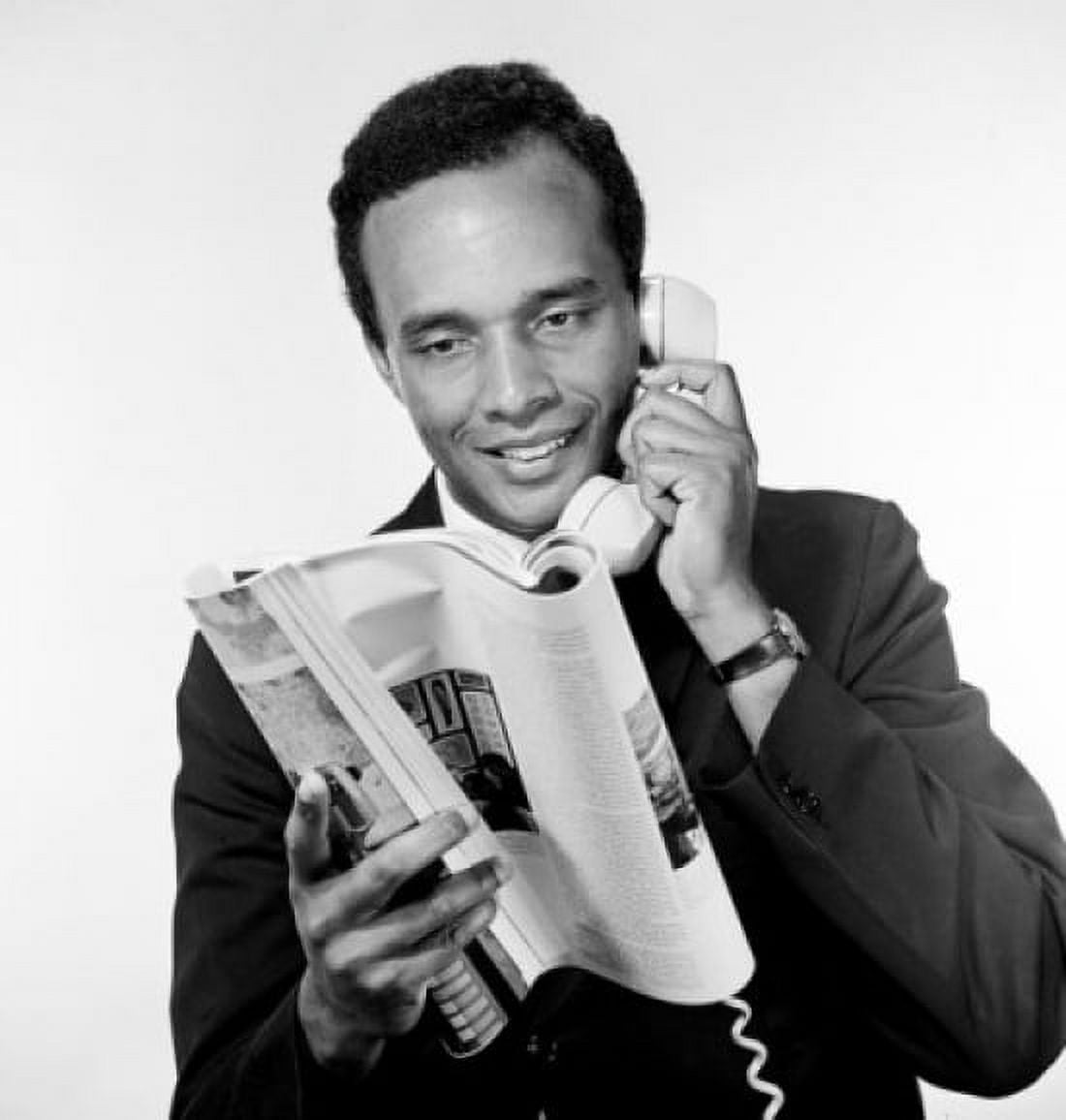 Portrait of African american man holding receiver and reading magazine studio shot Canvas Art - (24 x 36)