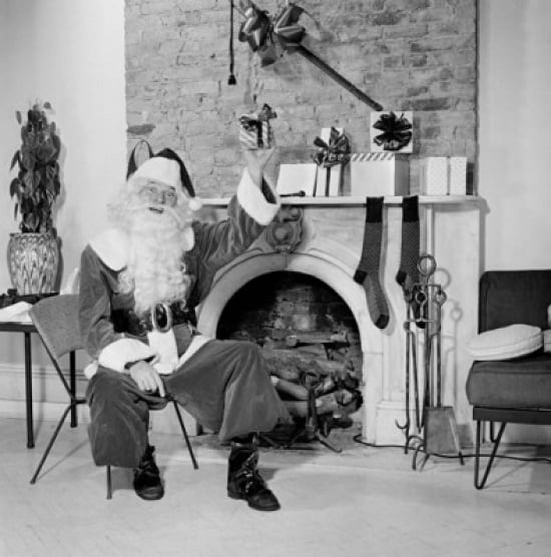 Portrait of Santa Claus sitting in front of a fireplace and holding a Christmas present Canvas Art - (18 x 24)