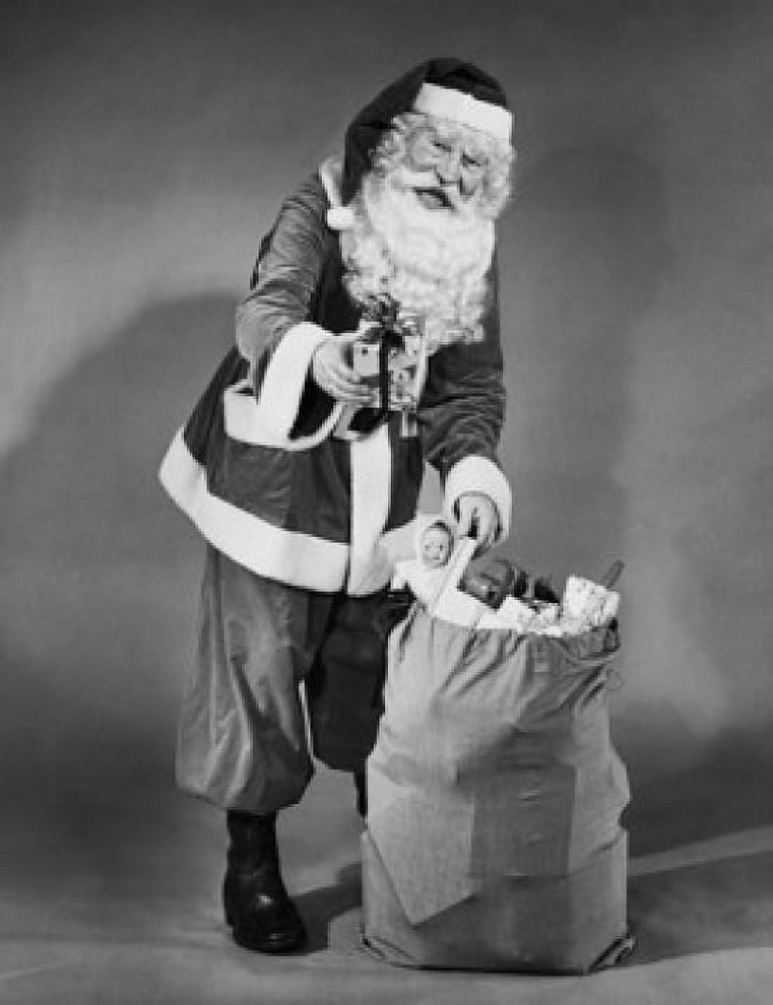 Portrait of Santa Claus standing with a sack of gifts and holding a Christmas present Canvas Art - (18 x 24)