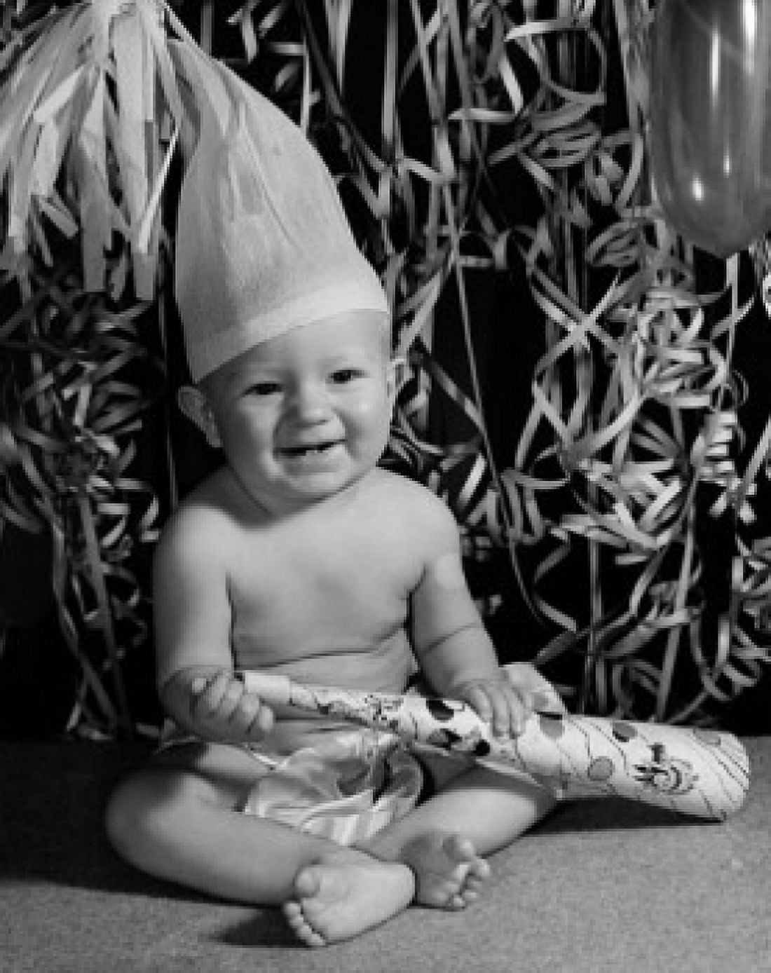 Portrait of a baby boy holding a noisemaker and smiling Canvas Art - (18 x 24)