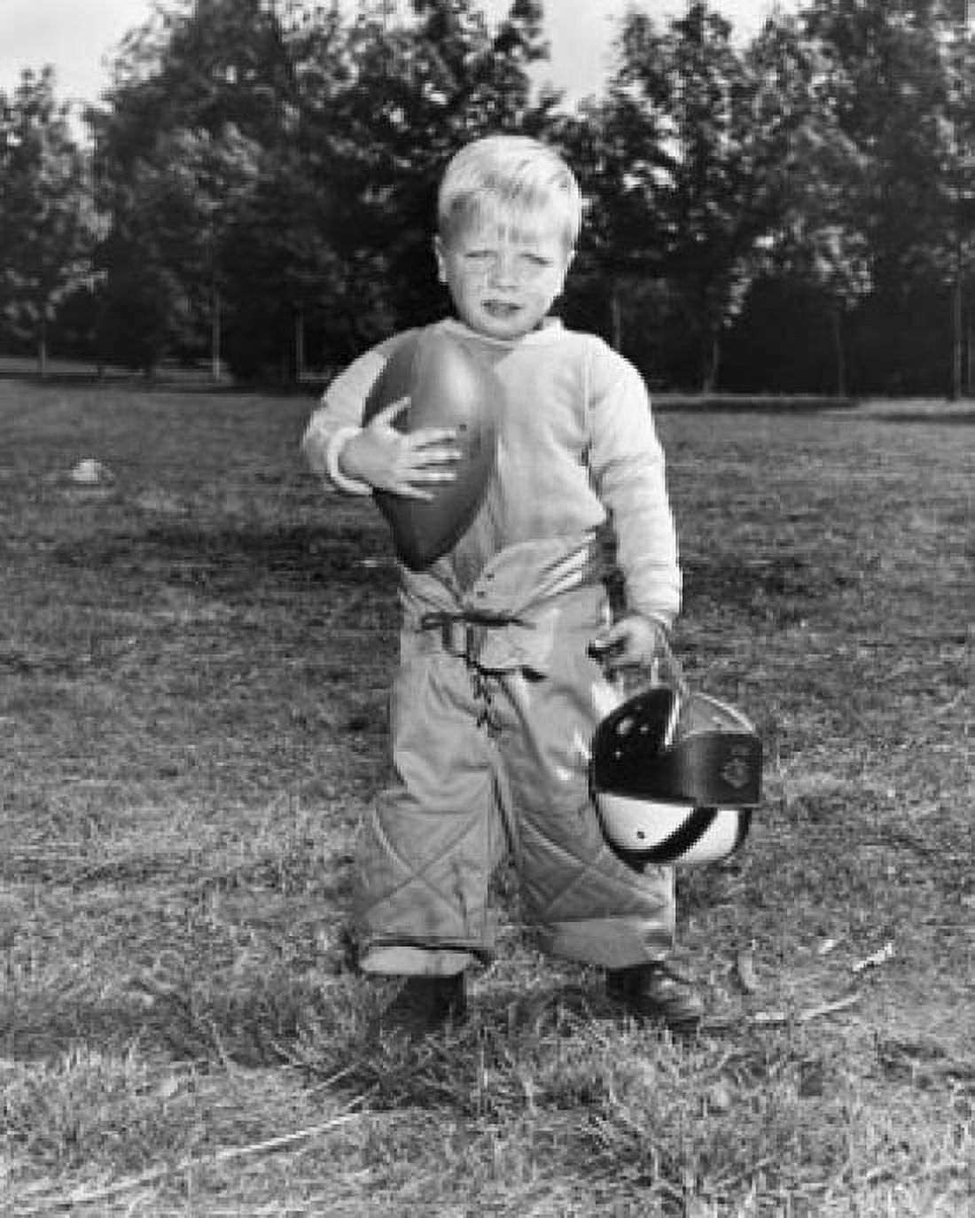 Portrait of a boy holding a football and a helmet Canvas Art - (24 x 36)