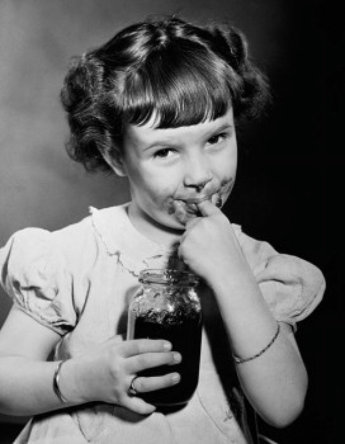 Portrait of a girl holding a jar of jam and licking her finger Canvas Art - (24 x 36)