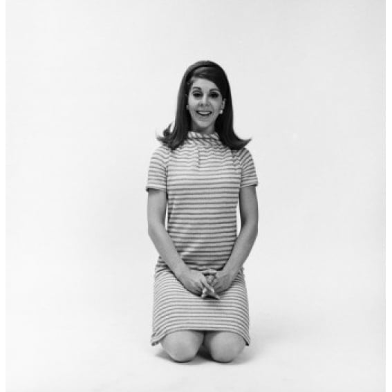 Portrait of a young woman kneeling on the floor and smiling Poster Print (24 x 36)