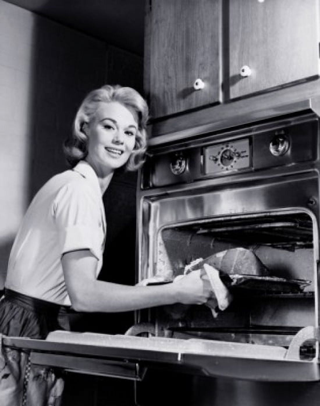 Portrait of a young woman putting meat into an oven Canvas Art - (18 x 24)