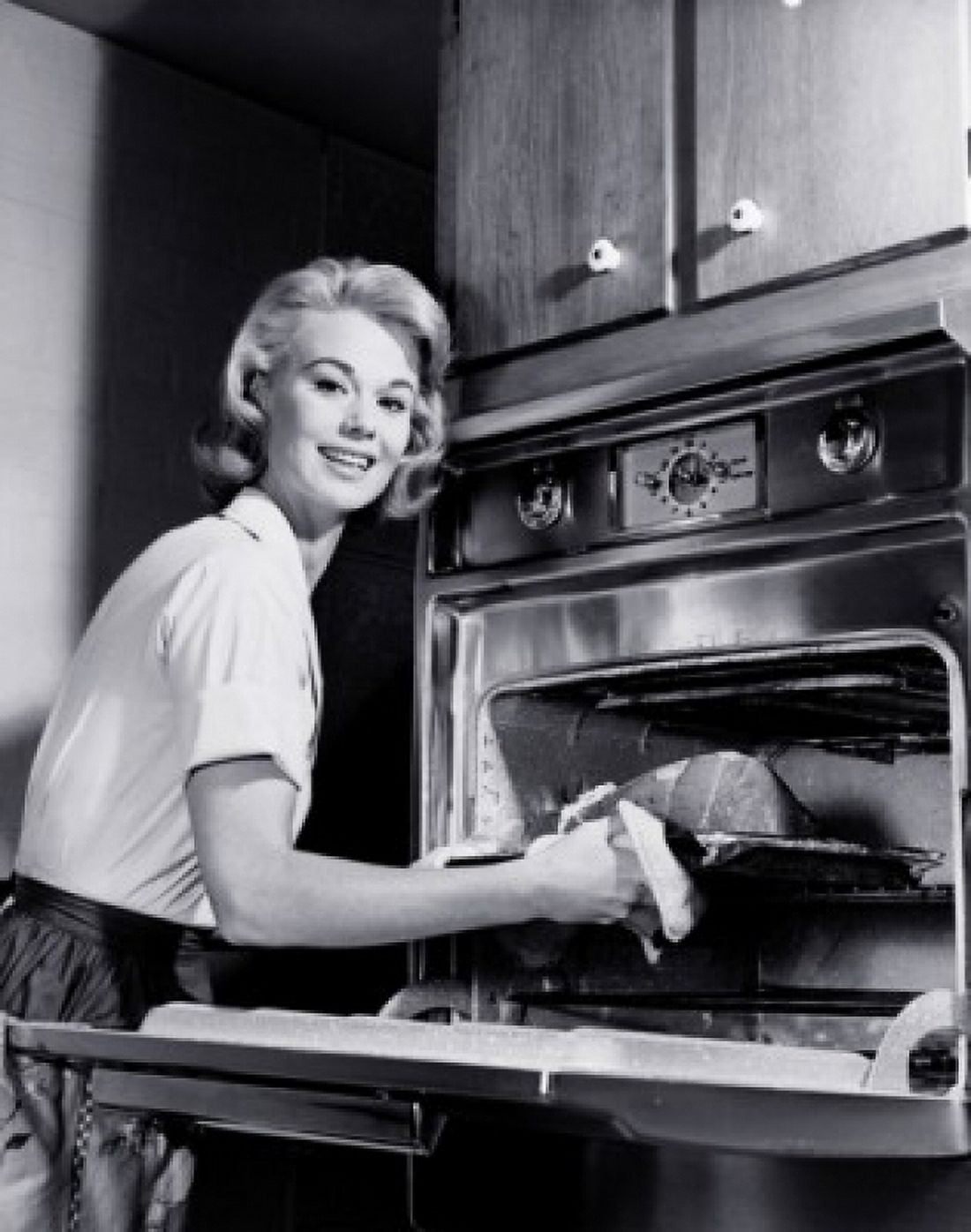 Portrait of a young woman putting meat into an oven Canvas Art - (24 x 36)