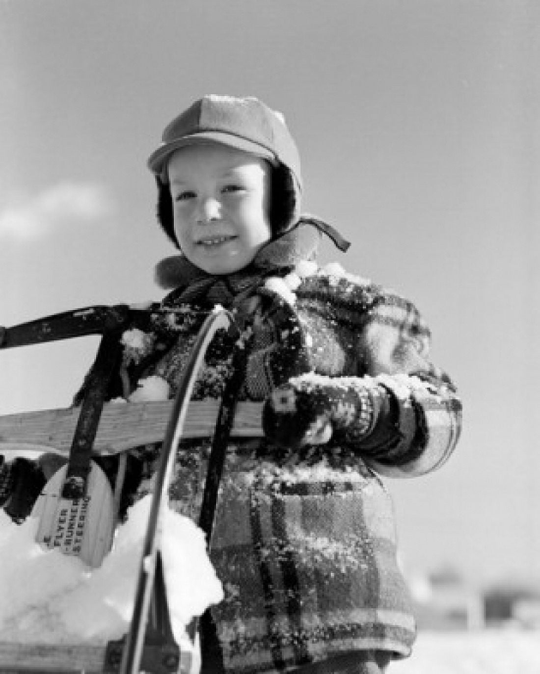 Portrait of boy covered with snow holding sleigh Canvas Art - (24 x 36)