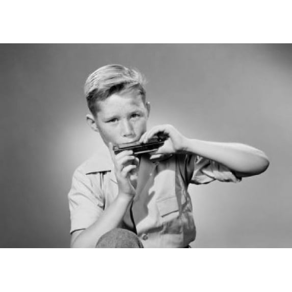 Portrait of boy playing harmonica, studio shot Poster Print (24 x 36)