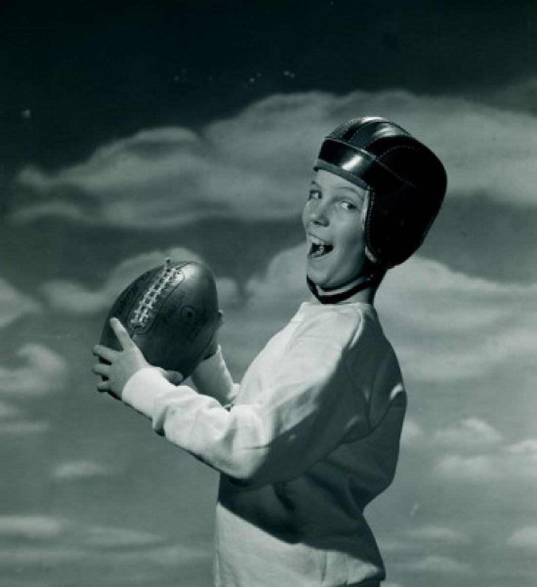 Portrait of boy wearing safety helmet holding American football Canvas Art - (18 x 24)