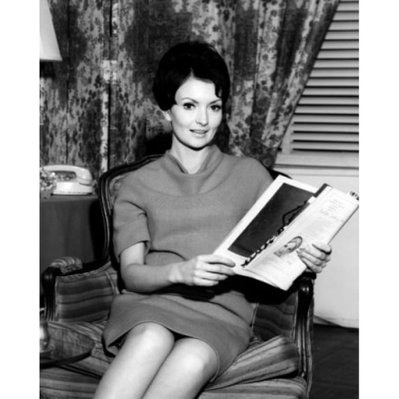 Portrait of mid adult woman in armchair reading magazine Poster Print (24 x 36)