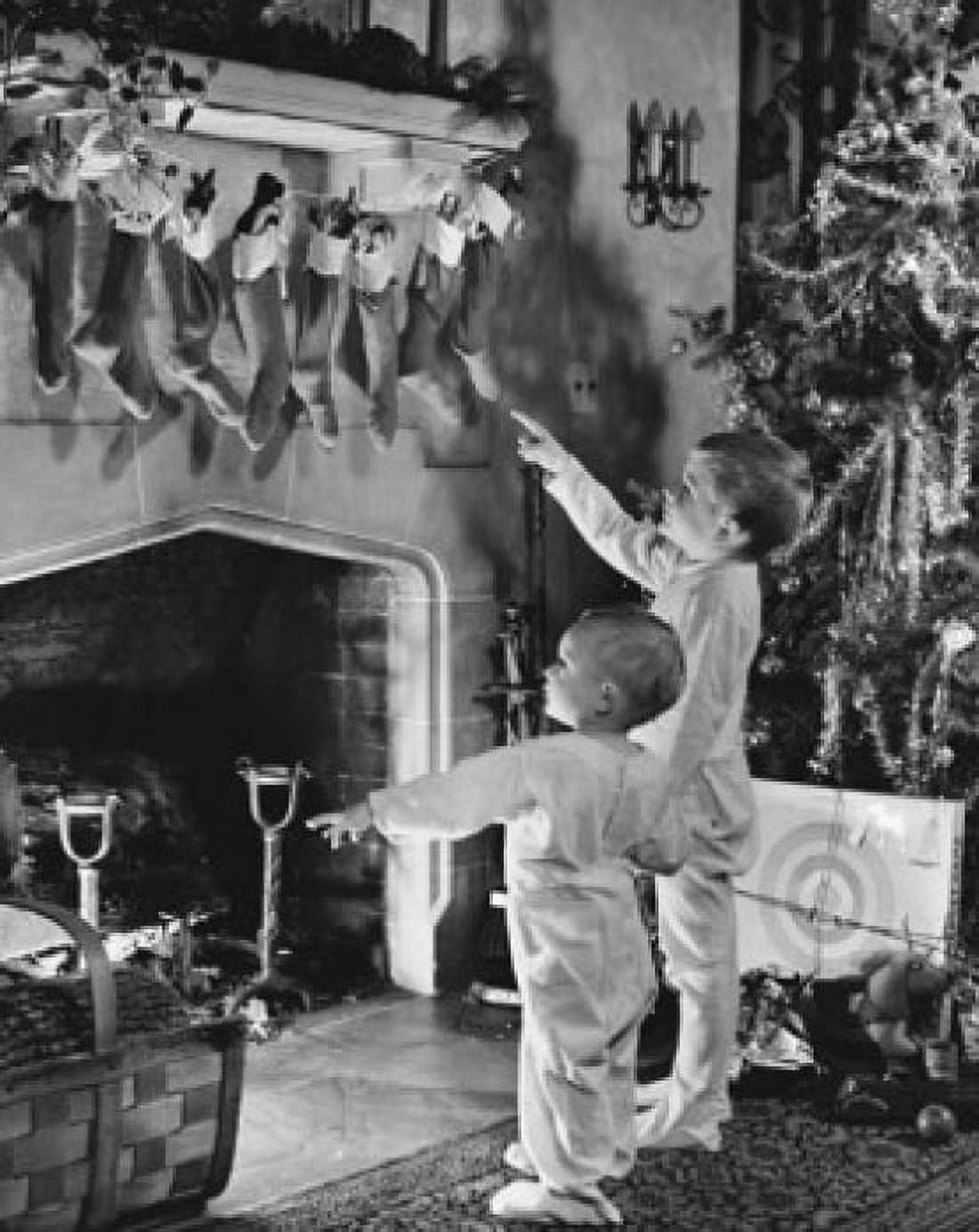 Posterazzi Boy standing with his brother in front of a fireplace and pointing at Christmas stockings Canvas Art - (24 x 36)