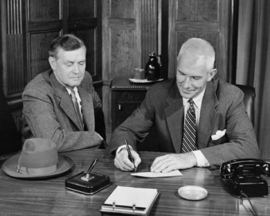 Posterazzi Businessman signing a check with another businessman sitting beside him Canvas Art -  (24 x 36)