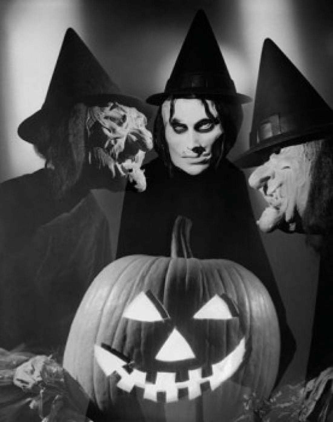Posterazzi Close-up of an illuminated jack o lantern with three people wearing Halloween costumes behind it Canvas Art -  (24 x 36)