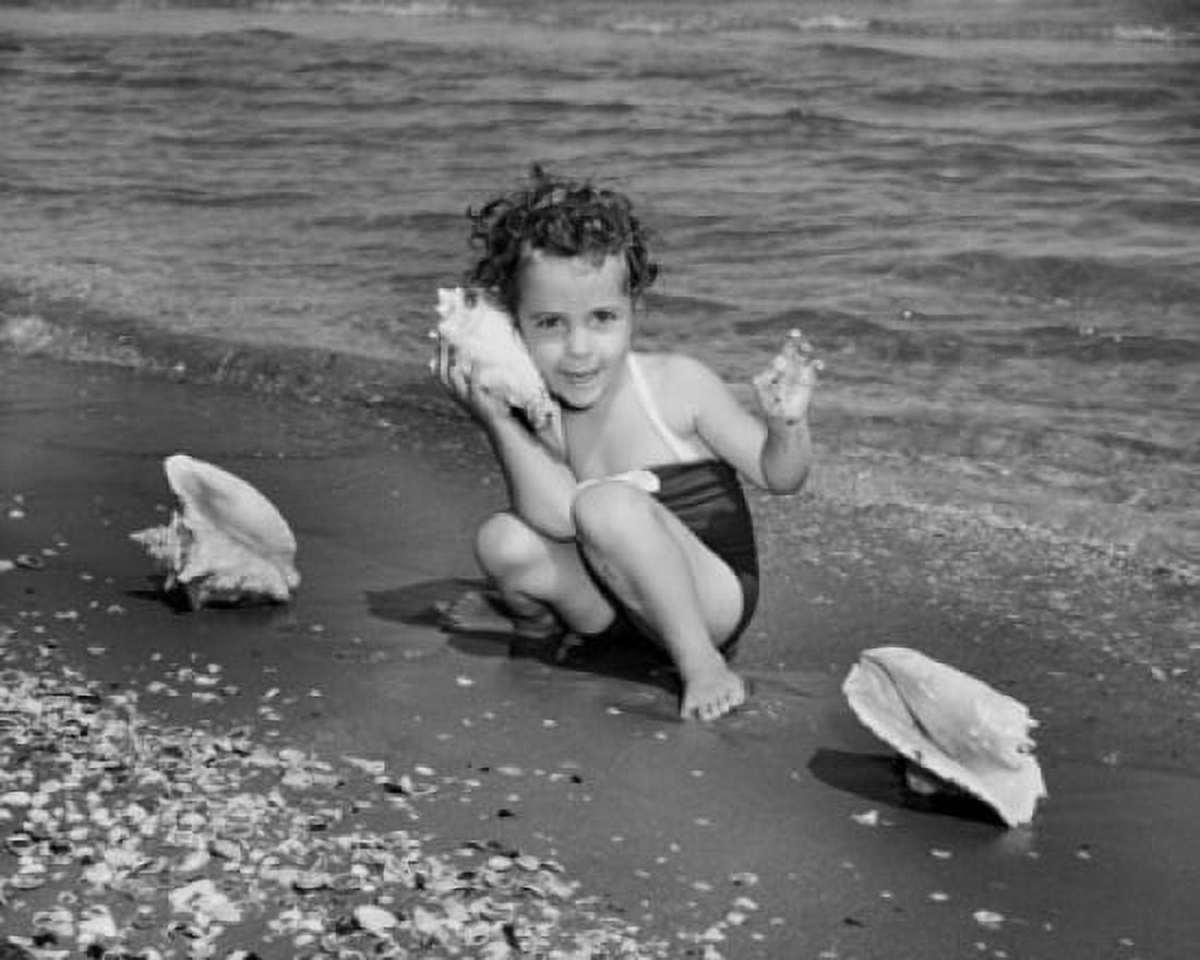 Posterazzi Girl holding a conch shell near her ear on the beach Canvas Art - (24 x 36)