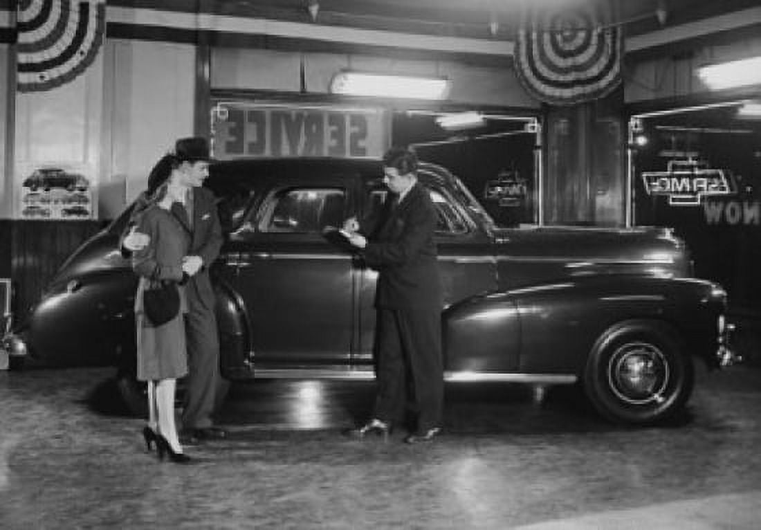 Posterazzi Salesman showing a car to a mid adult couple in a car showroom Chevrolet 1946 Canvas Art - (24 x 36)