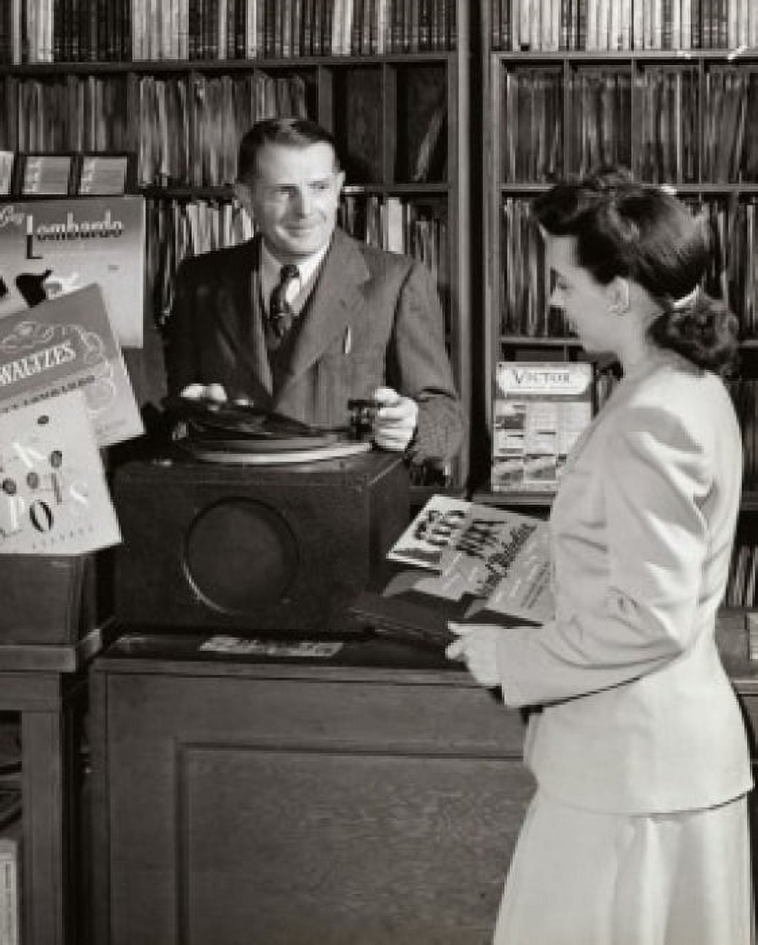 Posterazzi Salesman showing a record to a young woman Canvas Art - (24 x 36)