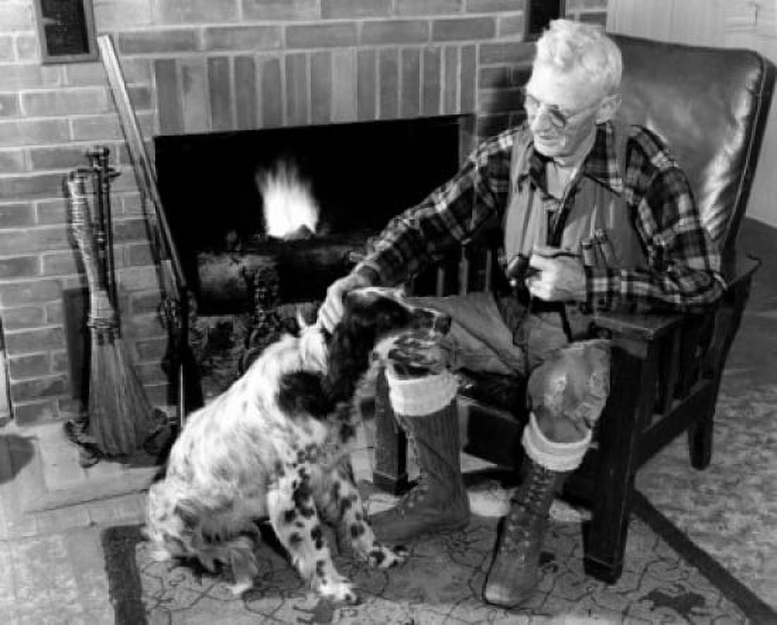 Posterazzi Senior man sitting next to fireplace stroking dog Canvas Art - (24 x 36)