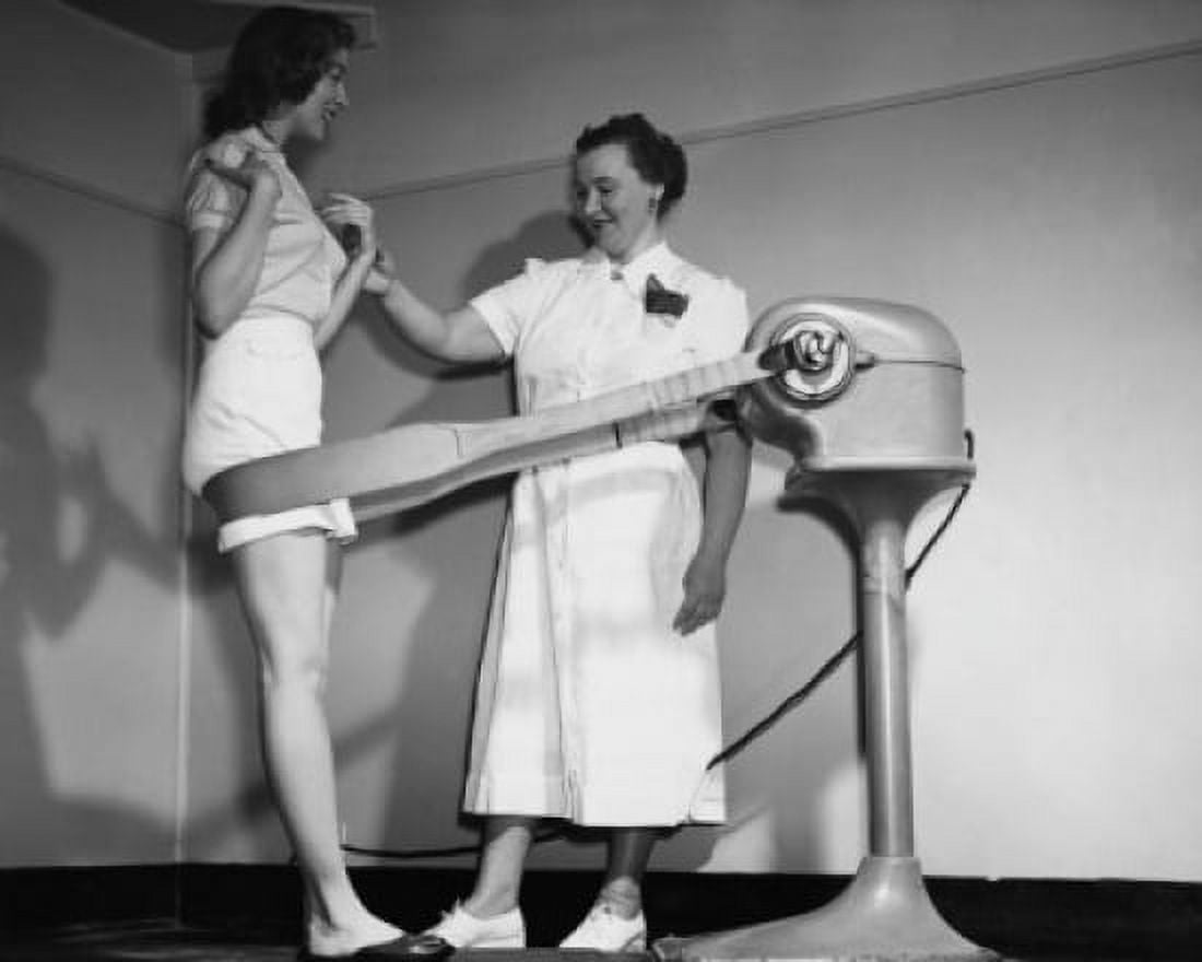 Posterazzi Side profile of a young woman leaning against the belt of a slimming machine with her instructor checking her pulse Canvas Art - (24 x 36)