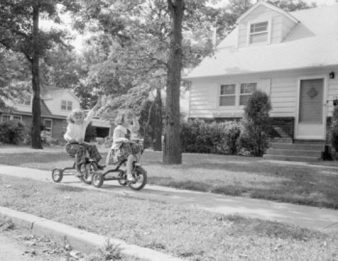 Posterazzi Two girls cycling in front of house Canvas Art - (24 x 36)