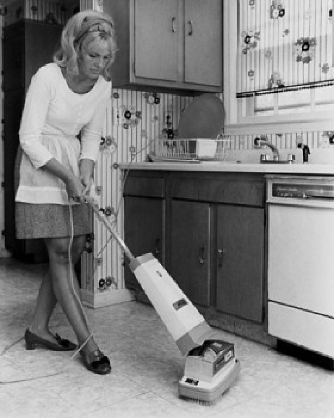 Posterazzi Young woman using vacuum cleaner in kitchen Canvas Art - (24 x 36)