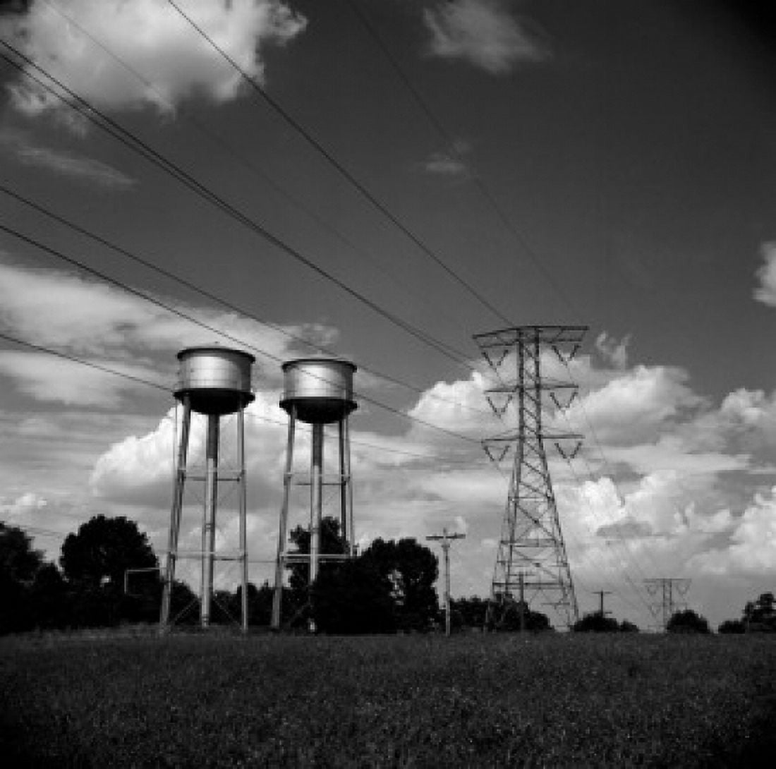 Power lines and water tanks against cloudy sky Canvas Art - (24 x 36)