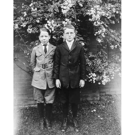 Print: Two Boys Posed, Standing In Front Of Wall And Blooming Tree, circa