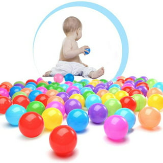 Toddler boy playing with a toy while sitting in a ball pit full of