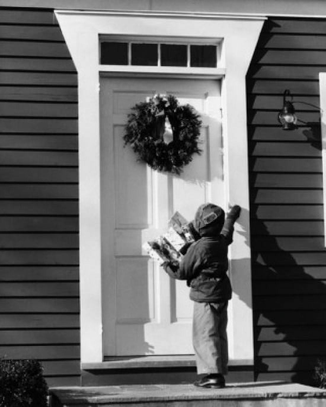 Rear view of a boy holding Christmas presents and standing in front of a closed door Canvas Art - (24 x 36)