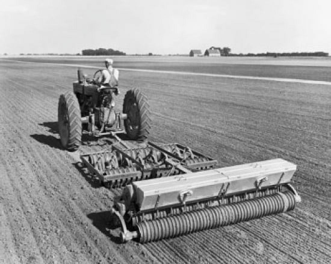 Rear view of a farmer sowing alfalfa and ladino clover seeds in a field with a tractor Canvas Art - (24 x 36)