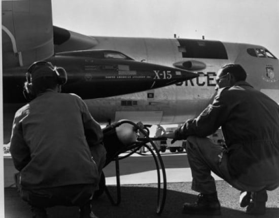 Rear view of two men crouching near fighter planes X-15 Rocket Research Airplane B-52 Mothership Canvas Art - (18 x 24)