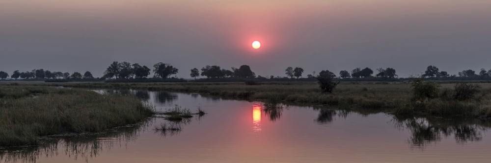 Reflection of sun in river at dusk Kings Pool Camp Linyanti Okavango Delta Botswana Canvas Art - Panoramic Images (27 x 9)