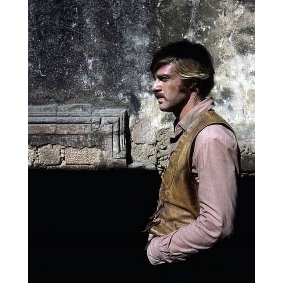 Reobert Redford stands in profile by wall Butch Cassidy The Sundance Kid poster