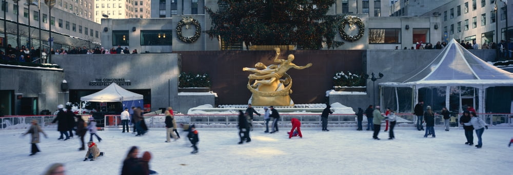 Rockefeller Square and ice skating rink and ice skaters at Christmas time with snow in mid-town Manhattan NY Canvas Art - Panoramic Images (36 x 12)