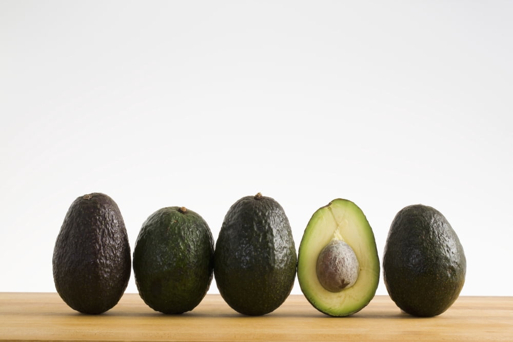 A Row Of Avocados Standing Upright On A Wooden Board With One Cut In Half With The Pit Calgary Alberta Canada Canvas Art - Michael Interisano Design Pics (38 x 24)