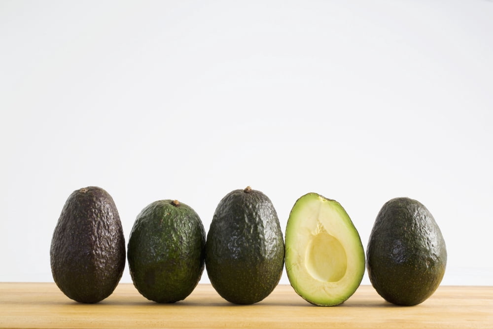 A Row Of Avocados Standing Upright On A Wooden Board With One Cut In Half Without The Pit Calgary Alberta Canada Canvas Art - Michael Interisano Design Pics (19 x 12)