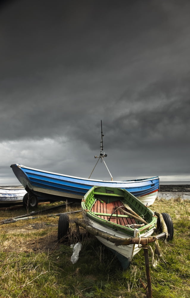 Rowboats sitting on trailers on the shore under storm cloudsBoulmer northumberland england Canvas Art - John Short  Design Pics (24 x 38)