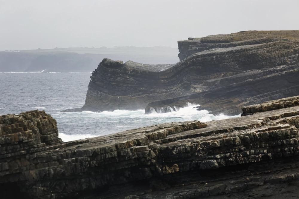 Rugged dark rocky cliffs with waves and fogged sky Kilkee County Clare Ireland Canvas Art - Michael Interisano Design Pics (38 x 24)