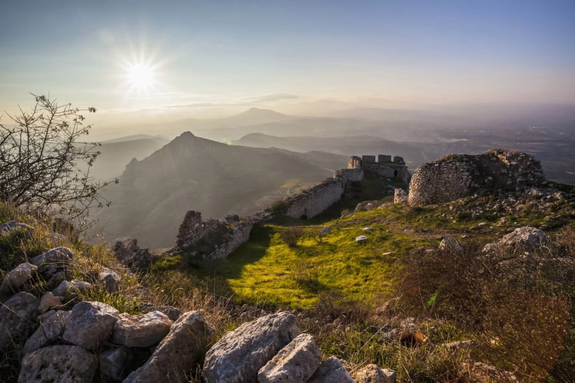 Ruins of a stone wall and buildings with a sunburst and mountains Corinth Greece Canvas Art - Reynold Mainse Design Pics (19 x 12)