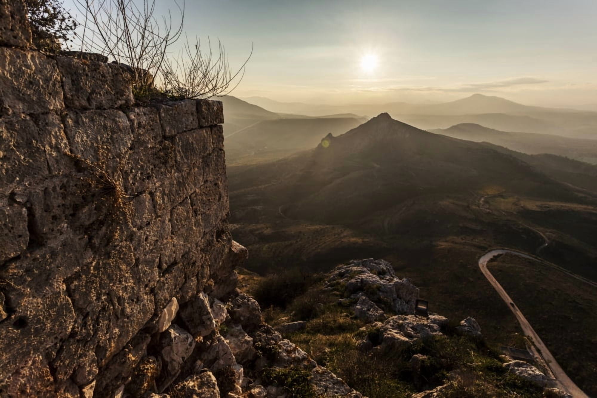 Ruins of a stone wall with a sunburst and mountains Corinth Greece Canvas Art - Reynold Mainse Design Pics (19 x 12)