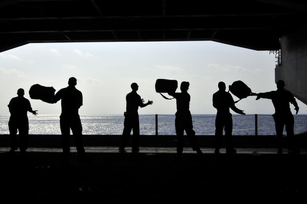 Sailors pass supplies to each other in the hangar bay of USS Ronald Reagan Canvas Art - Stocktrek Images (34 x 23)