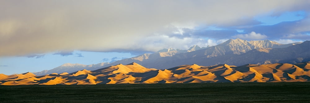 Sand dunes in a desert with a mountain range in the background Great Sand Dunes National Park Colorado USA Canvas Art - Panoramic Images (27 x 9)