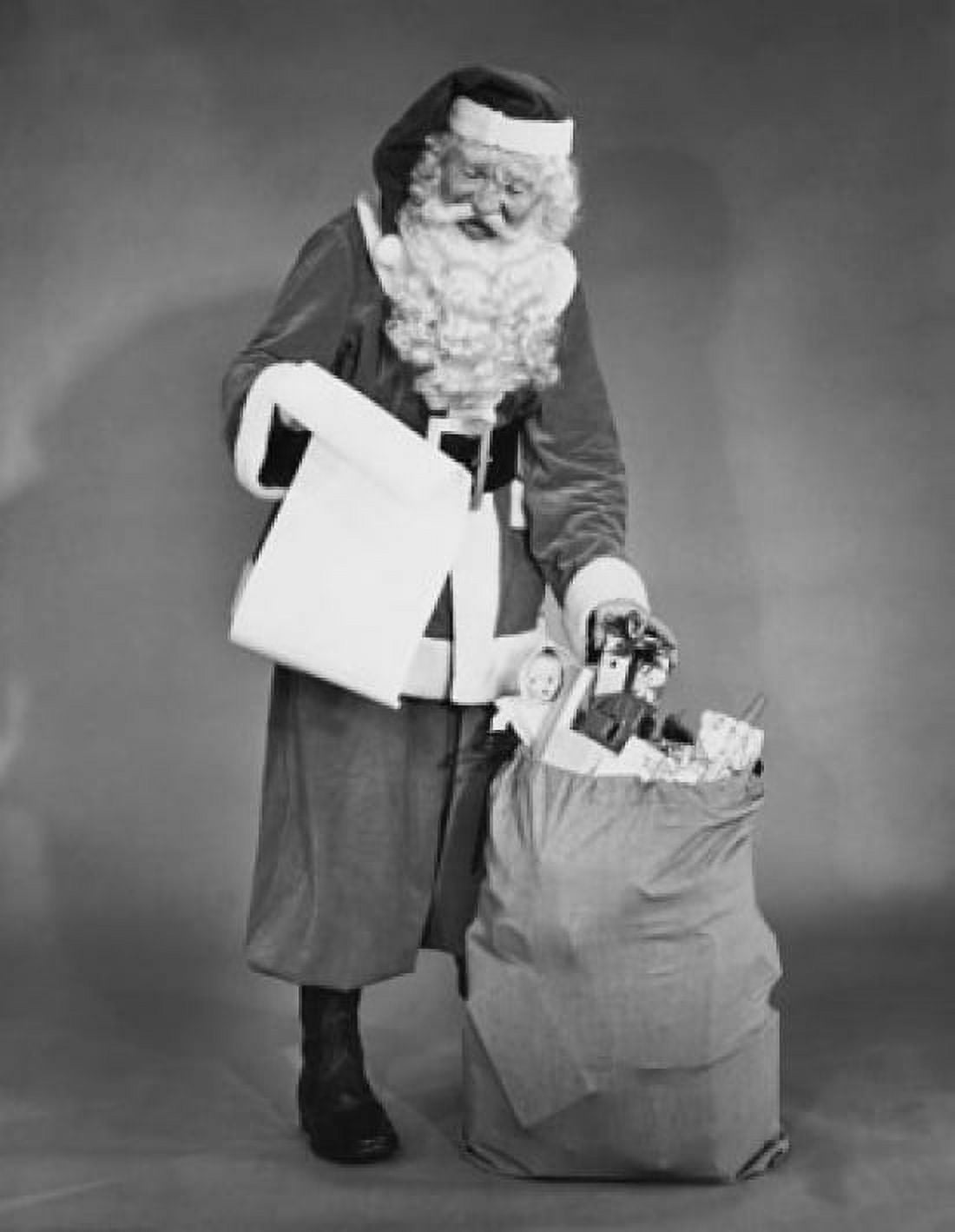 Santa Claus standing near a sack of gifts and checking a list of names Canvas Art - (24 x 36)